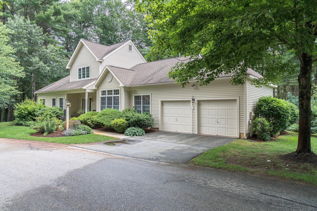 a front view of a house with a garden and trees