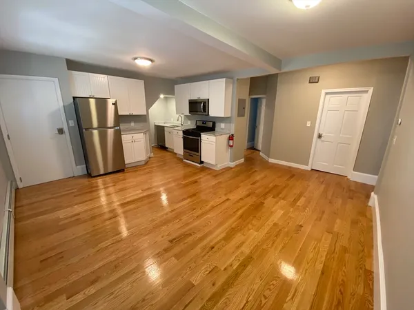 a large room with kitchen wooden floor and refrigerator