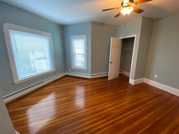 an empty room with wooden floor and windows