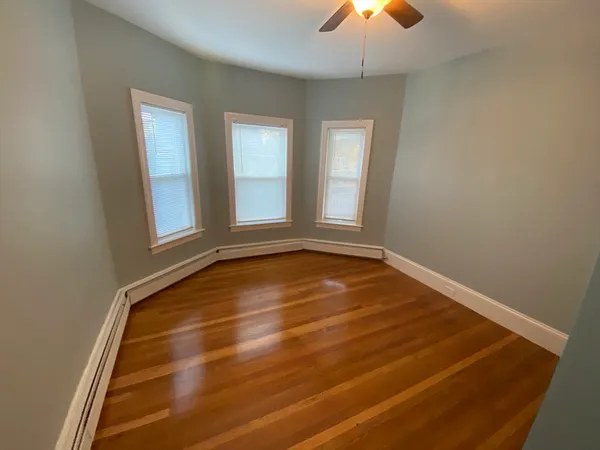 an empty room with chandelier fan and windows