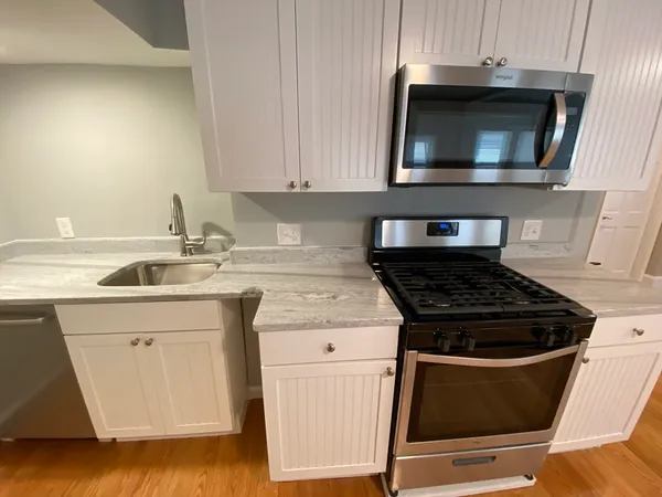 a kitchen with granite countertop white cabinets and stainless steel appliances