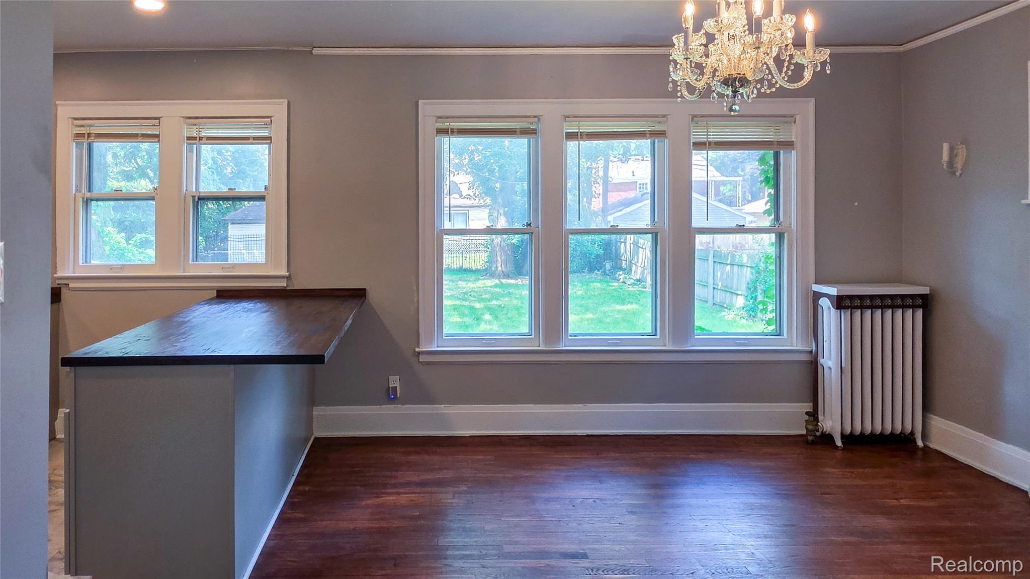 16715 Edinborough Road Detroit, MI 48219 - Photo 6 of 21 Hardwood flooring, multiple windows, built-in breakfast bar with wood countertop, crystal chandelier, and a classic radiator