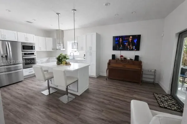a living room with furniture a flat screen tv and kitchen view