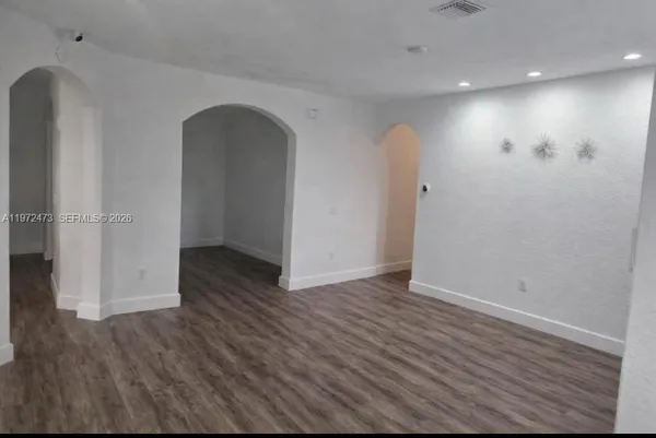 an empty room with wooden floor and entrance