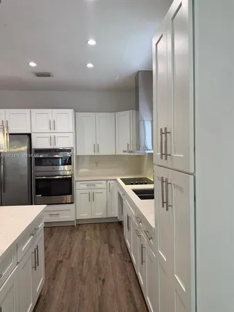 a kitchen with granite countertop stainless steel appliances and white cabinets