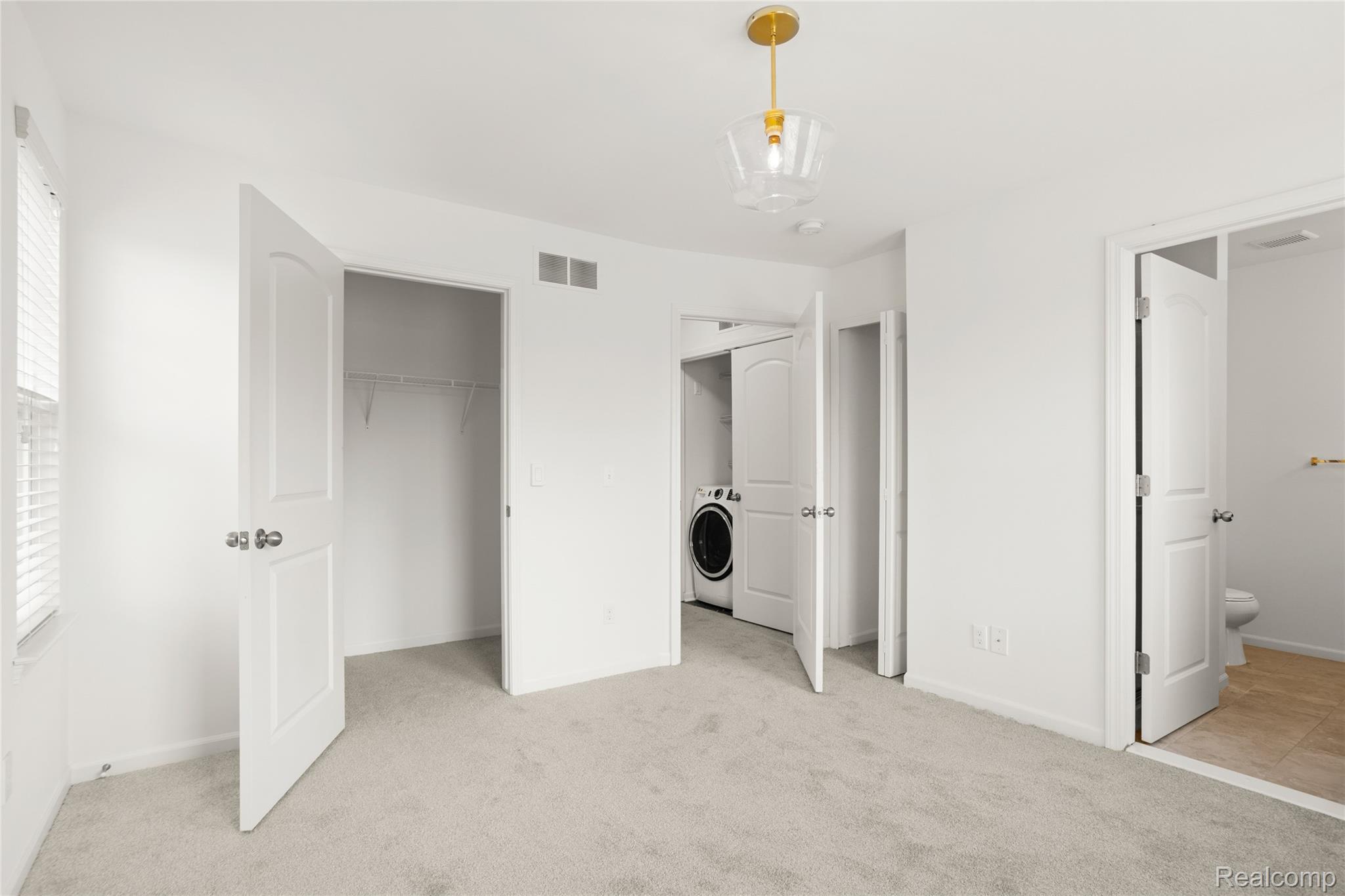 478 North Wixom Road Wixom, MI 48393 - Photo 13 of 26 Unfurnished bedroom featuring light carpet, washer / dryer, a closet, and ensuite bathroom