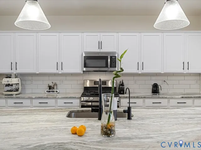 a kitchen with stainless steel appliances kitchen island granite countertop a stove and a white cabinets