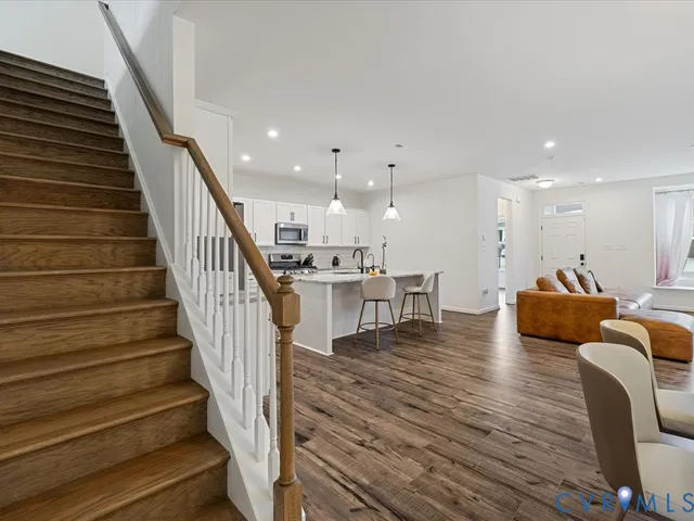 a living room with furniture and kitchen view with wooden floor
