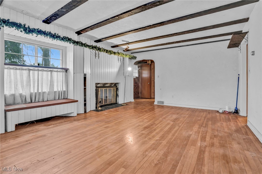 4468 Fishcreek Road Stow, OH 44224 - Photo 5 of 38 Living area featuring a fireplace with flush hearth, visible vents, hardwood / wood-style flooring, beam ceiling, and radiator