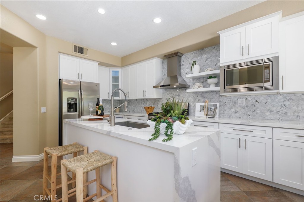 73 Blazewood Lake Forest, CA 92610 - Photo 13 of 53 a kitchen with stainless steel appliances kitchen island granite countertop a refrigerator a stove a sink dishwasher and white cabinets with wooden floor