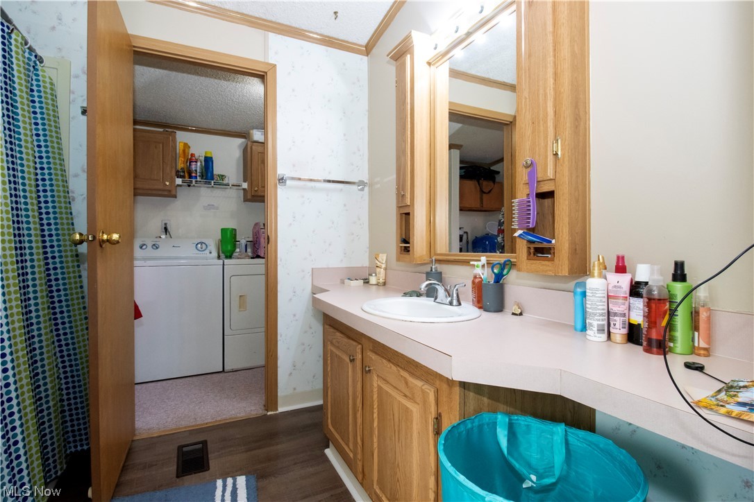 3233 Dover Road Wooster, OH 44691 - Photo 28 of 30 Bathroom with hardwood / wood-style floors, crown molding, washing machine and clothes dryer, a textured ceiling, and vanity with extensive cabinet space