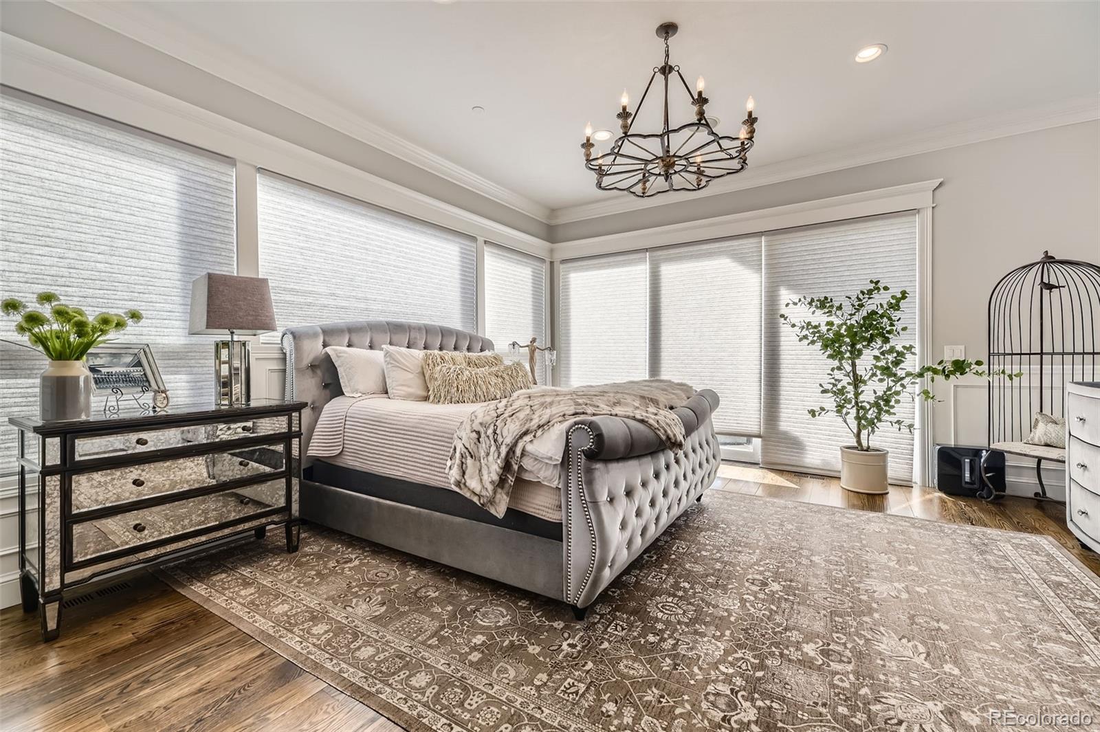 1050 Buffalo Ridge Road Castle Pines, CO 80108 - Photo 16 of 50 a bedroom with a large bed and a chandelier