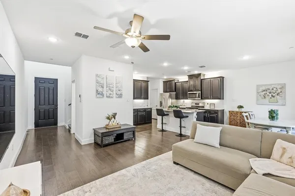 a living room with furniture kitchen view and a wooden floor