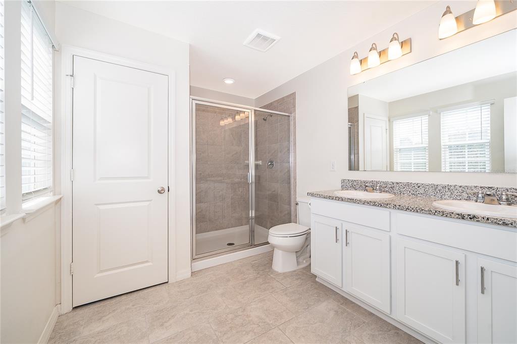 5849 Soter Lane Windermere, FL 34786 - Photo 18 of 31 a bathroom with a granite countertop sink a toilet and a shower