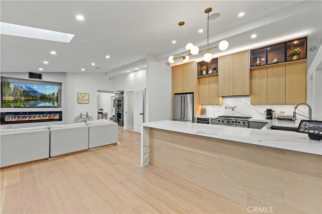 22263 Flanco Road Woodland Hills, CA 91364 - Photo 19 of 69 a large room with kitchen island a flat screen tv a island and stainless steel appliances