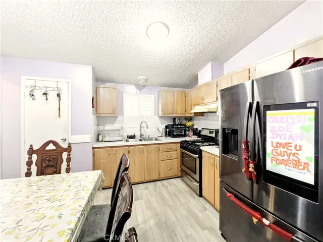 a kitchen with stainless steel appliances sink stove refrigerator dining table and chairs