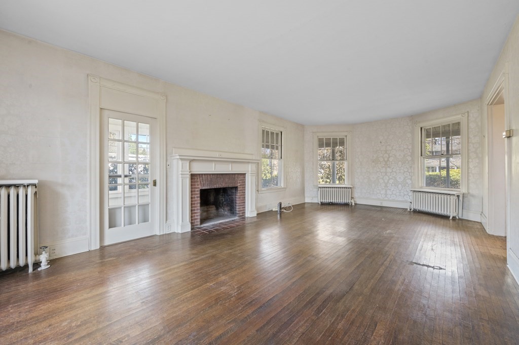 97 Beach Bluff Avenue Swampscott, MA 01907 - Photo 11 of 36 an empty room with wooden floor fireplace and windows