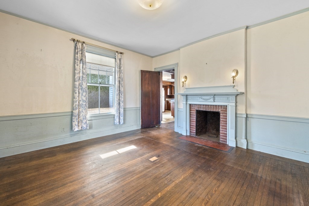97 Beach Bluff Avenue Swampscott, MA 01907 - Photo 13 of 36 a view of an empty room with wooden floor fireplace and a window