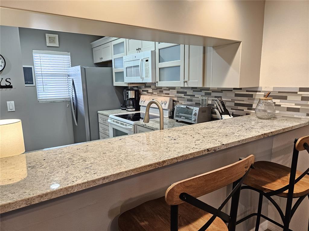 435 Cerromar Lane, Unit 329 Venice, FL 34293 - Photo 37 of 59 a kitchen with granite countertop a sink chairs and refrigerator