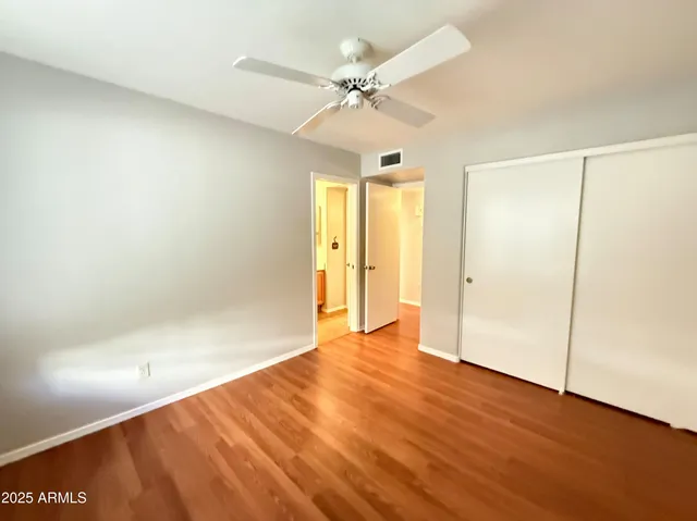 an empty room with wooden floor and fan