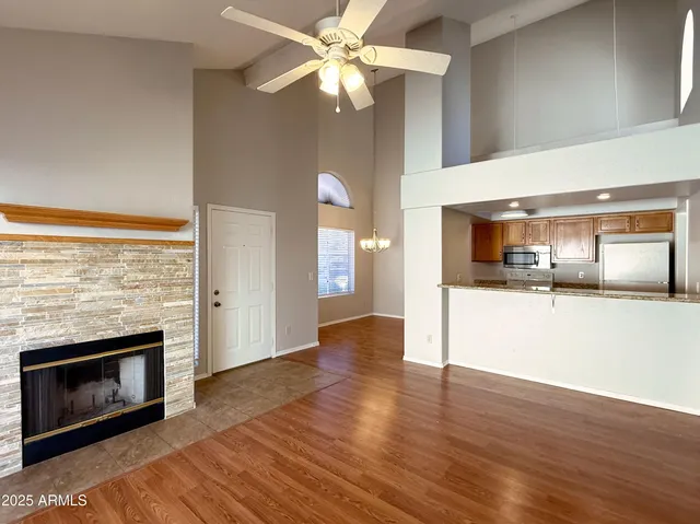 a view of a kitchen and an empty room with wooden floor