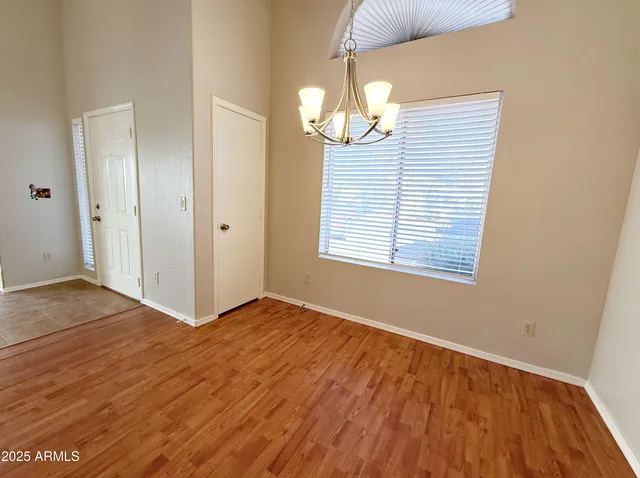 an empty room with wooden floor chandelier and windows