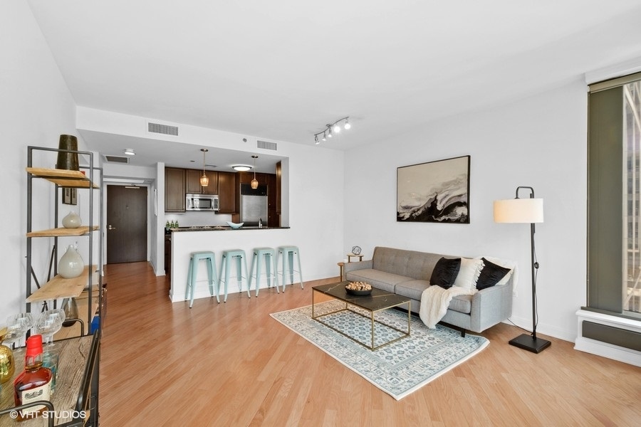 60 East Monroe Street, Unit 2005 Chicago, IL 60603 - Photo 4 of 13 a living room with furniture and a flat screen tv