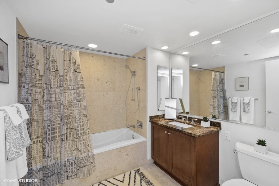 60 East Monroe Street, Unit 2005 Chicago, IL 60603 - Photo 8 of 13 a bathroom with a granite countertop sink a toilet a mirror and bathtub