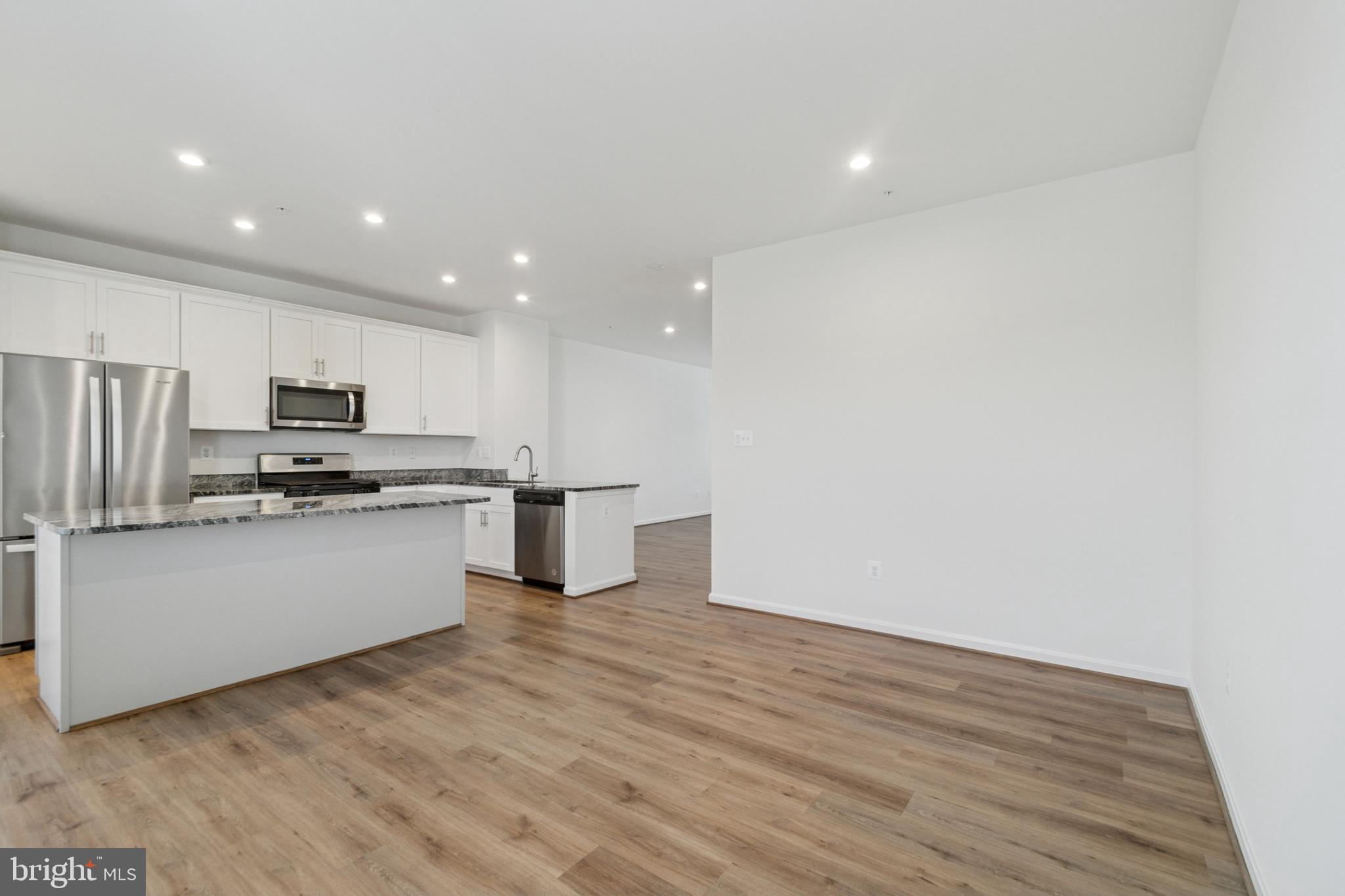 7811 Wolf Run Lane Severn, MD 21144 - Photo 5 of 32 a kitchen with stainless steel appliances wooden floor sink and wooden cabinets
