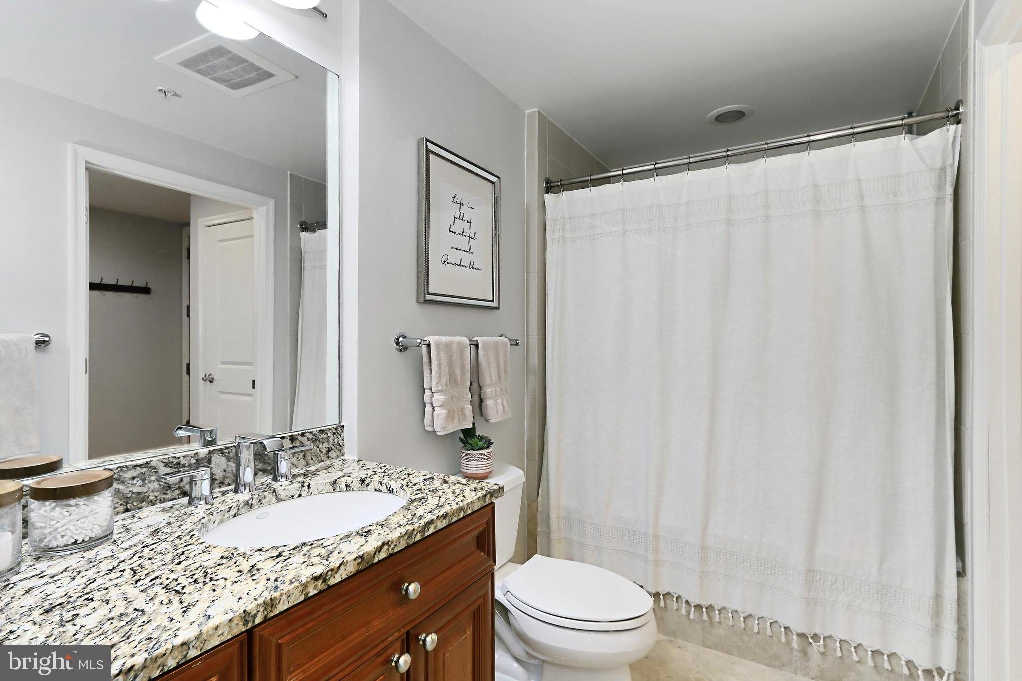 11990 Market Street, Unit 908 Reston, VA 20190 - Photo 15 of 45 a bathroom with a granite countertop sink toilet and shower
