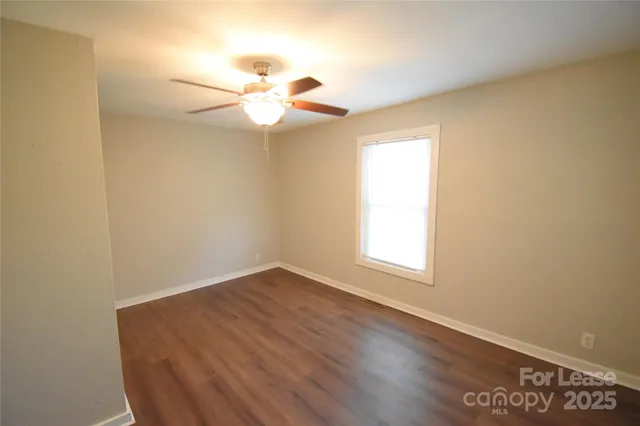 an empty room with wooden floor fan and window
