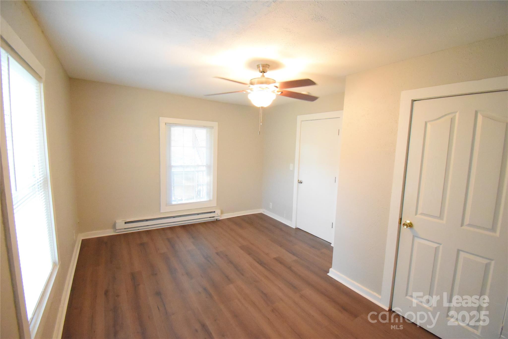 337 Fox Street Southwest Concord, NC 28025 - Photo 10 of 16 an empty room with wooden floor chandelier fan and windows