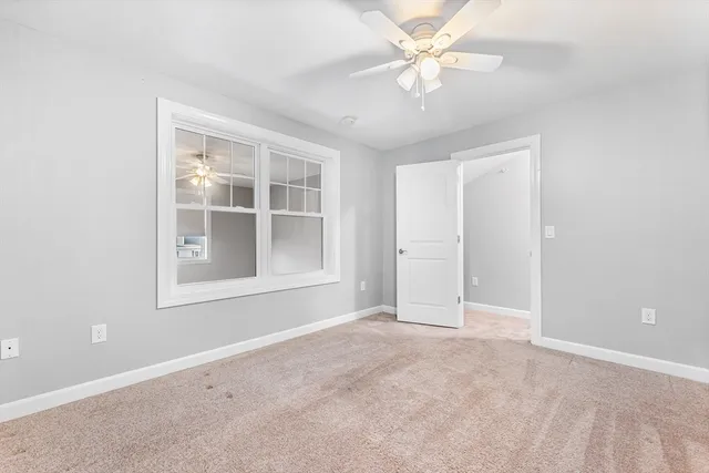 an empty room with chandelier fan and windows