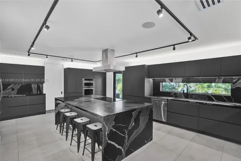 a kitchen with stainless steel appliances kitchen island granite countertop a table chairs and a refrigerator