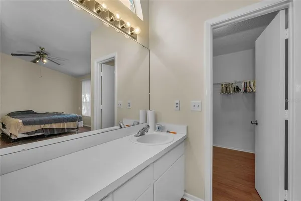 an empty room with wooden floor a ceiling fan and windows