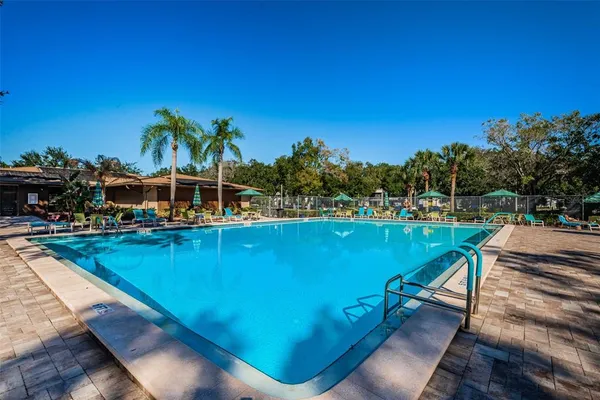 a view of a swimming pool with lawn chairs & wooden fence