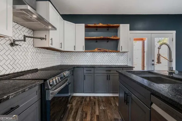 a kitchen with granite countertop a sink a stove and cabinets