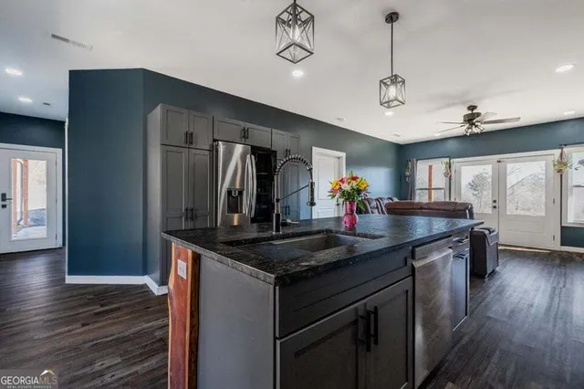 a kitchen with stainless steel appliances granite countertop a sink a refrigerator and wooden floor