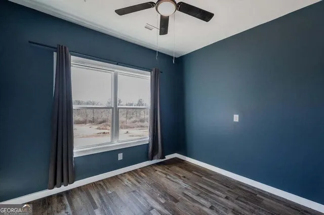 a view of an empty room with window and wooden floor