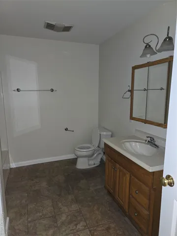 a bathroom with a granite countertop toilet a sink and a mirror