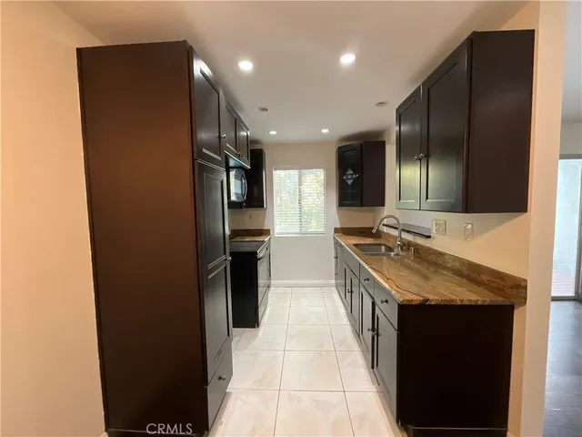 a large kitchen with granite countertop a sink and refrigerator