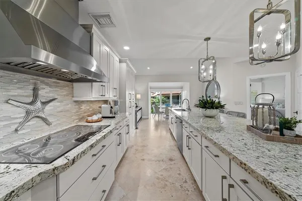 a large kitchen with stainless steel appliances kitchen island granite countertop a large stove a sink dishwasher and white cabinets with wooden floor