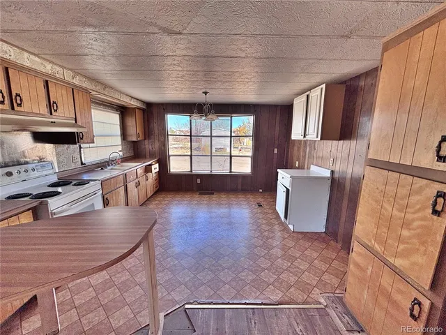 a large kitchen with stainless steel appliances granite countertop a stove a refrigerator a sink dishwasher a dining table and chairs with wooden floor