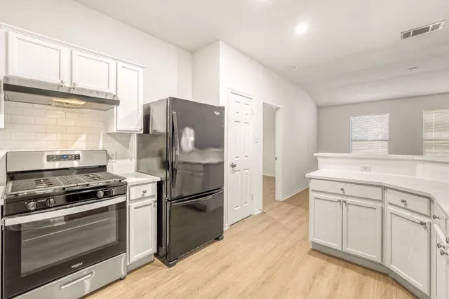 a kitchen with white cabinets and appliances