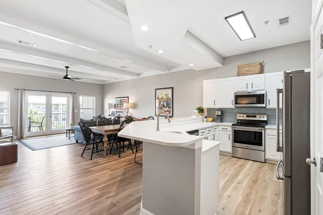 a large open kitchen with a refrigerator a stove top oven a sink dishwasher and white cabinets with wooden floor