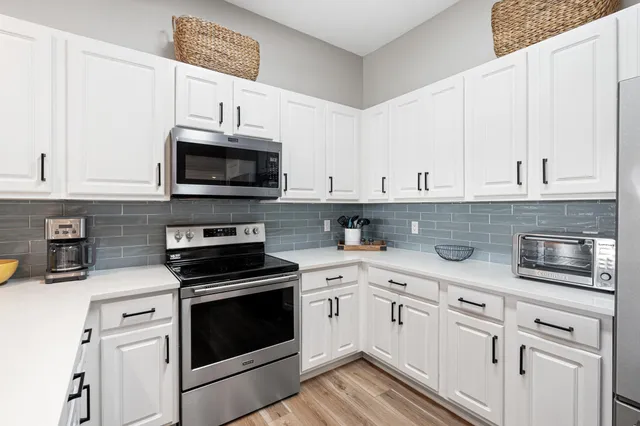 a kitchen with white cabinets and appliances