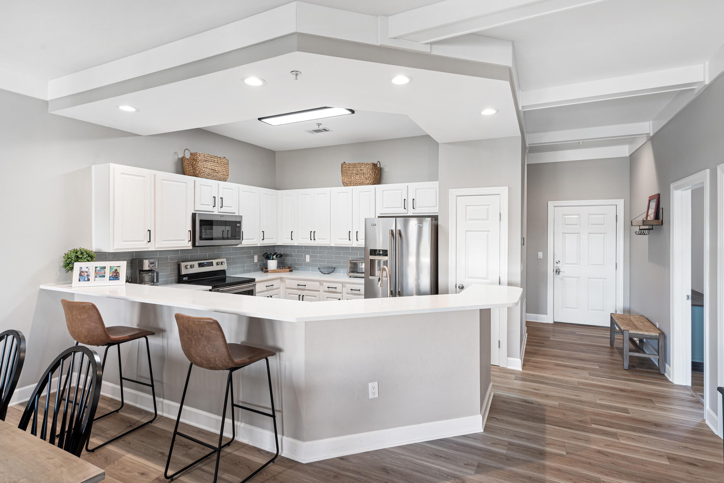 2410 Scenic Gulf Drive, Unit 201C Miramar Beach, FL 32550 - Photo 10 of 39 a kitchen with stainless steel appliances a refrigerator a stove a sink a dining table and chairs with wooden floor