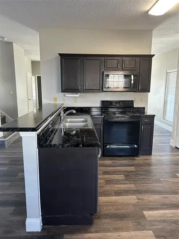 a kitchen with stainless steel appliances granite countertop a stove a sink and a microwave