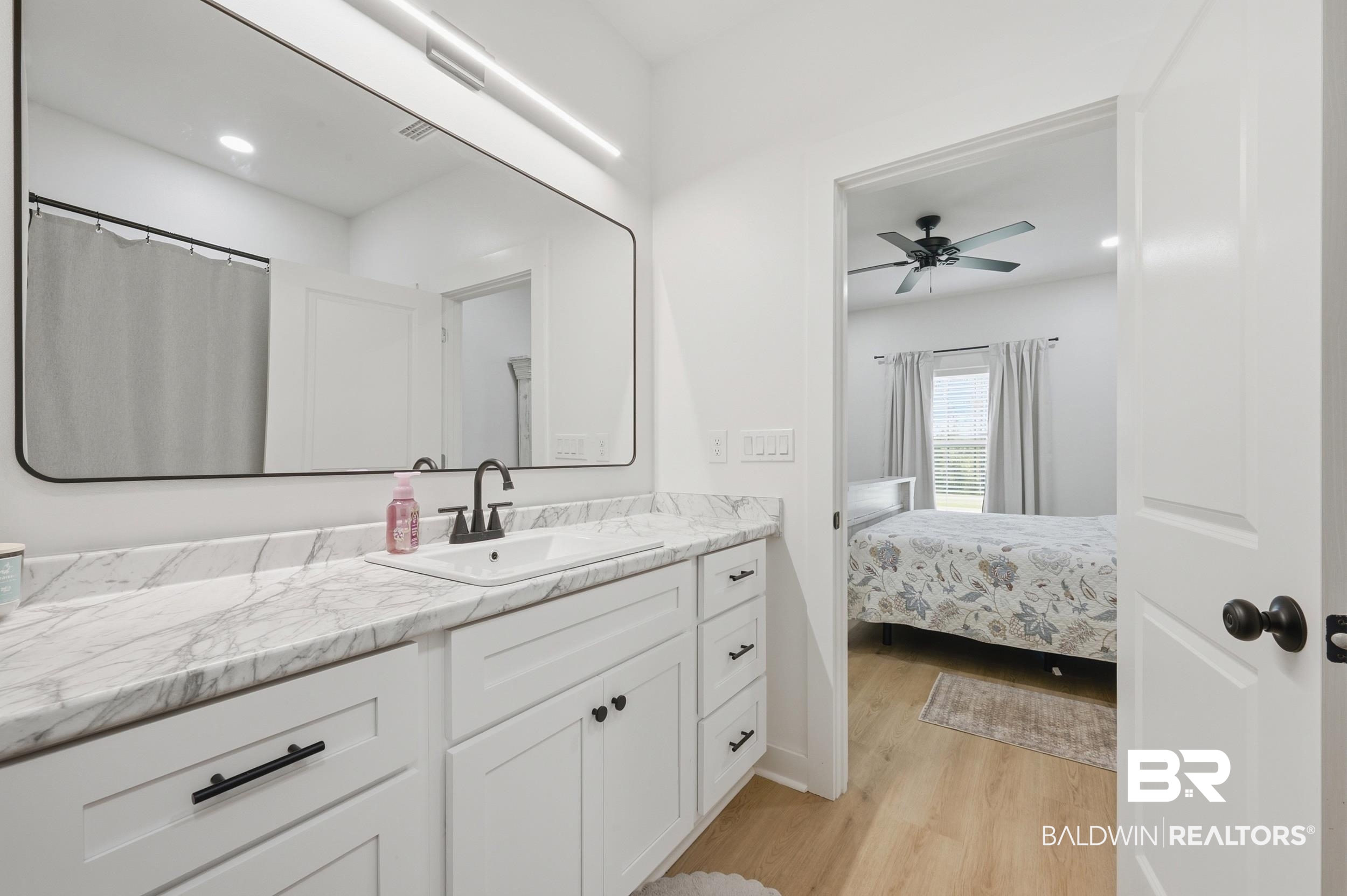 12019 Red Hill Rd Extension Bay Minette, AL 36507 - Photo 30 of 48 Bathroom vanity featuring a single basin, dark-finish faucet, and a large rectangular mirror with an integrated light bar