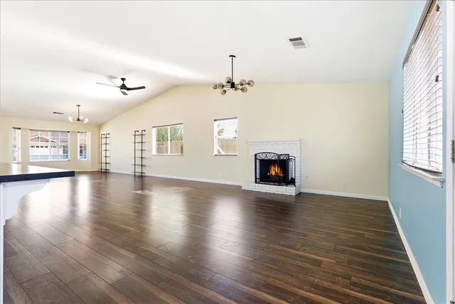 an empty room with wooden floor fireplace and windows
